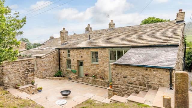 Stone farmhouse with a slate roof, surrounded by greenery and a stone patio, located in a rural Yorkshire setting.