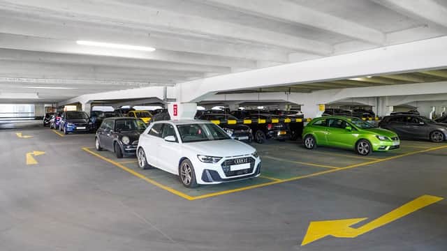 Multi-storey car park with parked cars, marked parking spaces, and directional arrows on the floor.