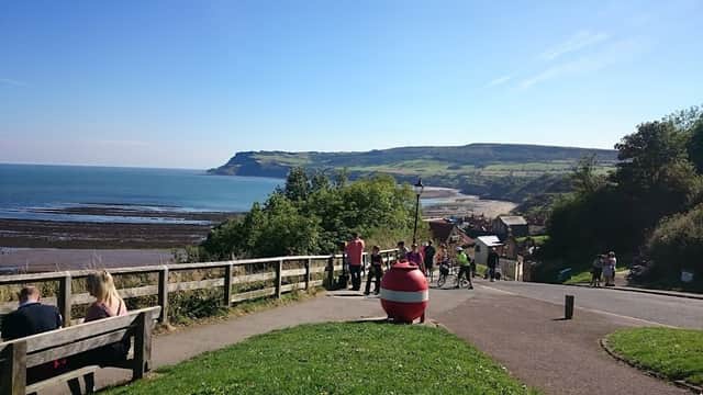 View of Bank Top Car Park with benches, a red pay display machine, and scenic coastline under a clear blue sky.