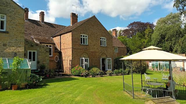 Newburgh House features a brick exterior, manicured lawn, garden plants, and a gazebo with seating in a serene setting.