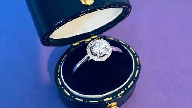 A sparkling diamond ring displayed in a black velvet-lined jewelry box.