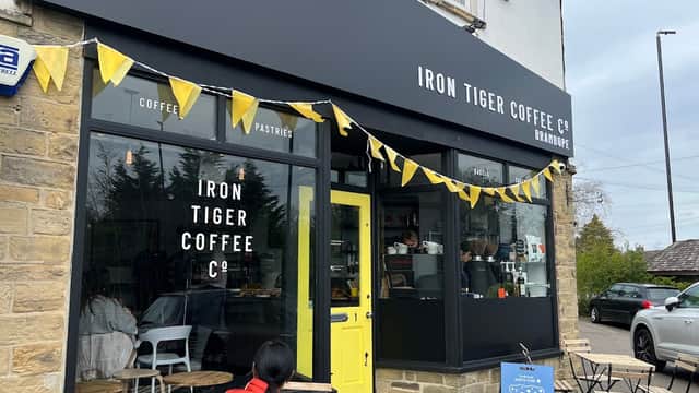 Black storefront with yellow accents, "Iron Tiger Coffee Co." sign, outdoor seating, and bunting in Bramhope, Yorkshire.