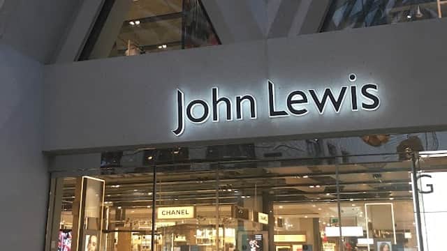 Entrance to John Lewis & Partners, featuring large glass doors and a modern architectural design, with store displays visible inside.