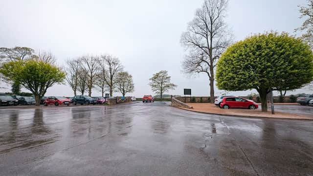 Car park with wet pavement, lined with trees, and parked cars under a cloudy sky in Wentworth, Yorkshire.