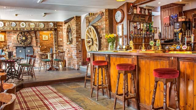 Warm wooden bar with red stools, dartboard, and rustic decor in a cozy pub setting.
