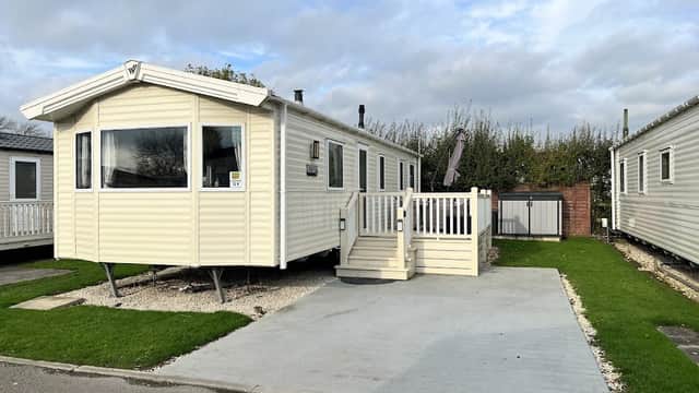 Holiday park caravan with a deck, surrounded by greenery and other caravans in Kirby Misperton, Yorkshire.