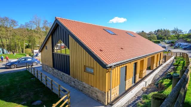 Modern wooden holiday cottage with a sloped roof, surrounded by greenery and a clear blue sky in North Yorkshire.