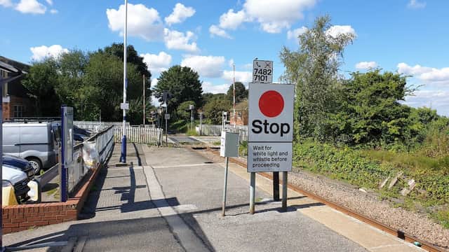 Railway station platform with a stop sign, tracks, and blue sky with clouds in East Cowick, Yorkshire.