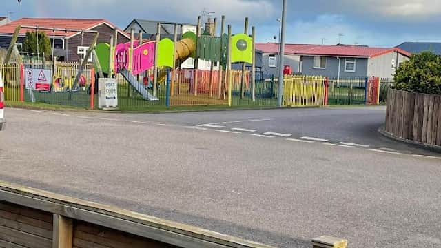 Colorful playground with slides and climbing structures, surrounded by holiday park accommodations under a cloudy sky.