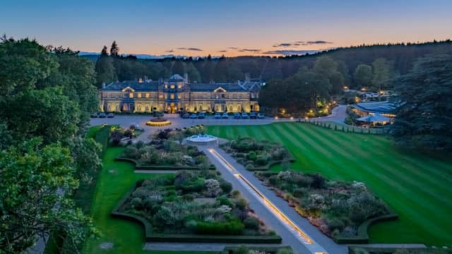 Elegant event venue at dusk, featuring manicured gardens, a fountain, and a grand building surrounded by trees.