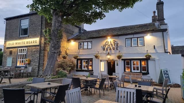 Historic pub with a sign reading "Old White Beare," outdoor seating, and a large tree in a quaint Yorkshire village.