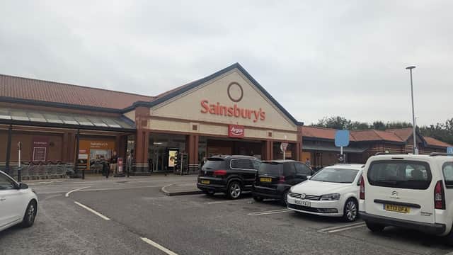Sainsbury's store front with Argos, parked cars, and cloudy sky in Colton, Yorkshire.