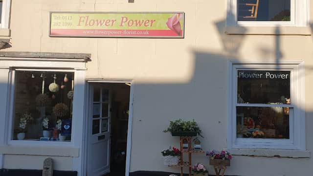 Brightly colored flower shop exterior with a sign reading "Flower Power" and floral displays in windows.