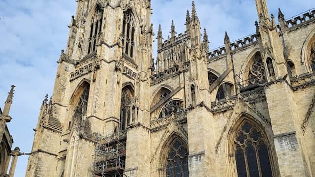 York Minster's towering gothic architecture, scaffolding on one side, under a partly cloudy sky.
