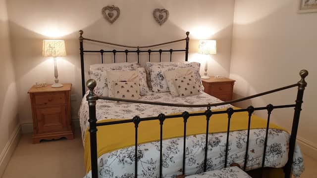 Cozy bedroom with an iron bed, floral bedding, wooden nightstands, and decorative lamps in a warm, inviting atmosphere.
