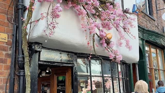 Jewellery shop with a wooden display, adorned with pink cherry blossoms and colorful birds, in York, Yorkshire.