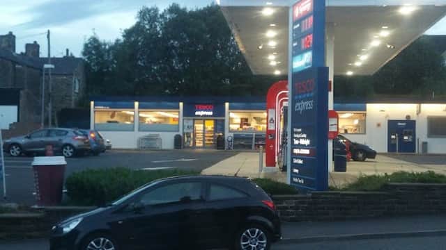 Tesco Esso Express shop with fuel pumps, parked cars, and a cloudy evening sky in Ovenden, Yorkshire.
