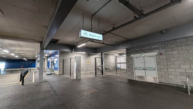 Bicycle parking area with a sign, bike racks, and a spacious concrete floor in a car park.