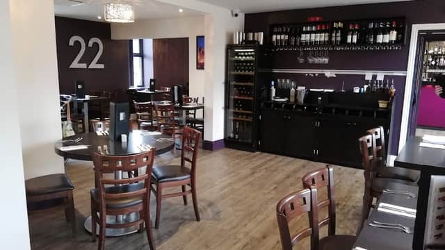 Modern dining area with wooden tables, chairs, wine rack, and purple accents, featuring the number 22 on the wall.