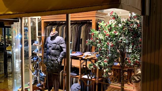 Shoe shop window display featuring clothing, shoes, and a decorative tree in Harrogate, Yorkshire.