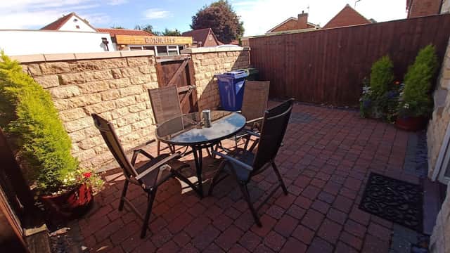Patio area with a round table and four chairs, surrounded by stone walls and potted plants in Seamer, Scarborough.