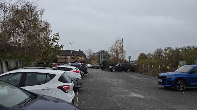 Car park in Malton, Yorkshire, with several parked cars and a cloudy sky in the background.