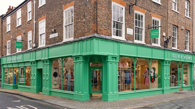 Green storefront of Oliver Bonas with large windows displaying colorful clothing and accessories in York, Yorkshire.