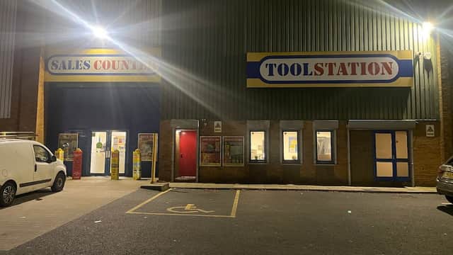 Toolstation storefront at night, featuring bright signage and a sales counter entrance, with parking spaces visible.