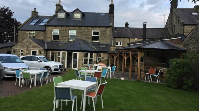 Charming outdoor seating area with colorful chairs, surrounded by a stone building and lush green lawn in Hampsthwaite.