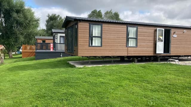 Two static caravans on a grassy area, surrounded by trees under a cloudy sky in Yafforth, Yorkshire.