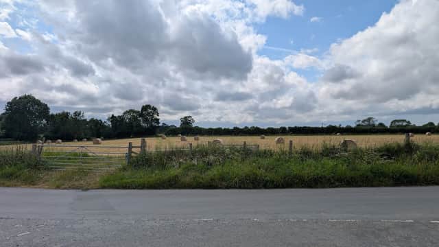 Rolling fields with hay bales, green trees in the background, and a cloudy sky near Upper Dunsforth Carrs Nature Reserve.