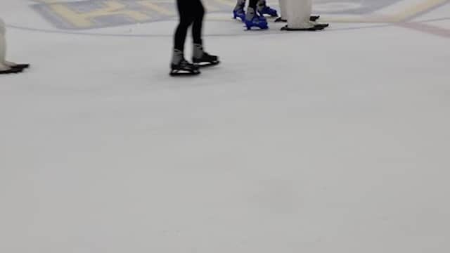 Skaters glide on ice at Elland Road's Park and Ride, with a rink backdrop and spectators in the stands.