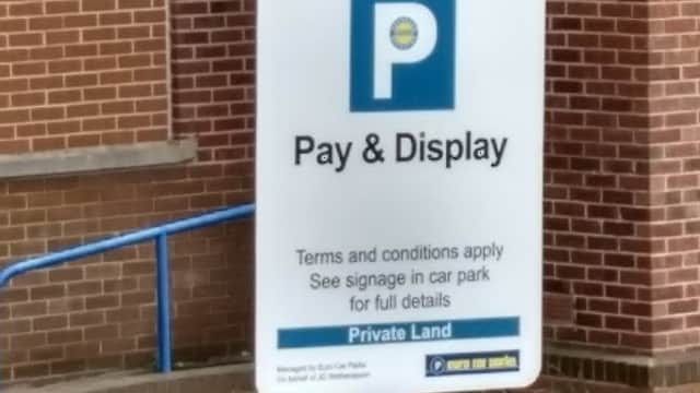 Sign for "Pay & Display" parking with terms and conditions, set against a brick wall in Montague Car Park, Mexborough.