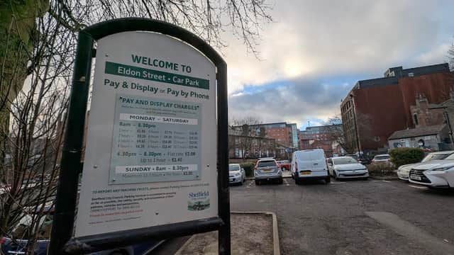 Welcome sign for Eldon Street Car Park with parking fees and hours, surrounded by parked cars and a cloudy sky.