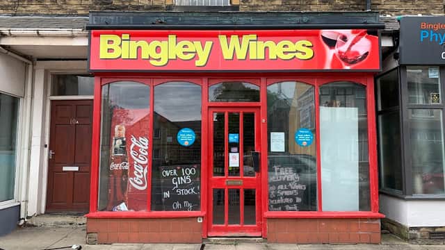 Bright red storefront with "Bingley Wines" sign, large windows, and promotional signs for gin and Coca-Cola.