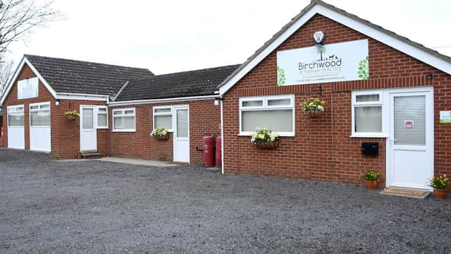 Birchwood Veterinary Practice building with brick exterior, white trim, flower pots, and a gravel parking area.