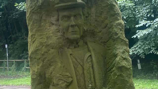 Stone sculpture of a man in a hat, set amidst greenery near Nidd Walk Parking in Pateley Bridge, Yorkshire.