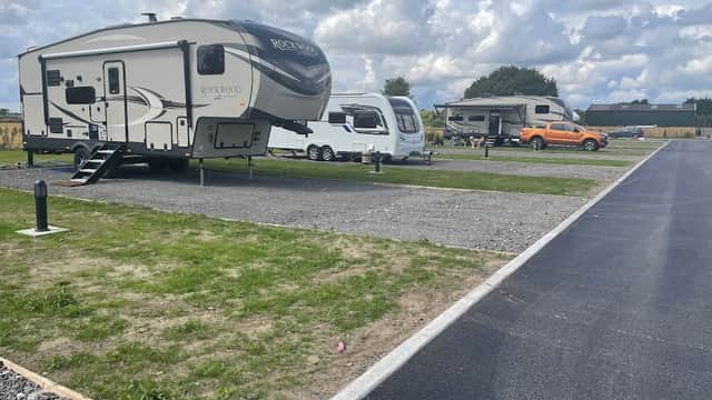 Campers parked on gravel at LINDA'S FARM, surrounded by green grass and cloudy skies in Cliffe Common, Yorkshire.