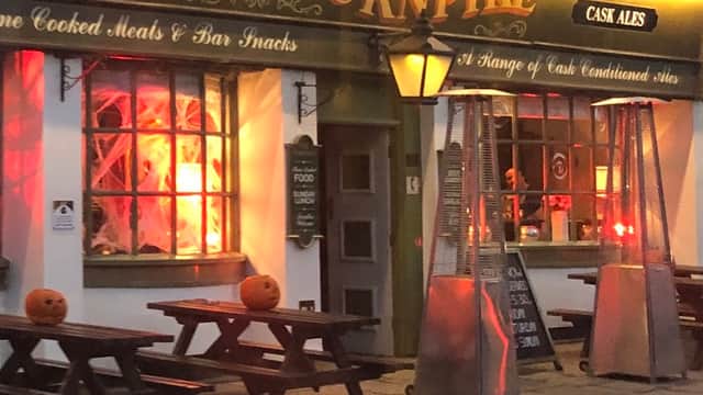The Turnpike bar features outdoor seating, glowing lanterns, and Halloween pumpkins on tables.