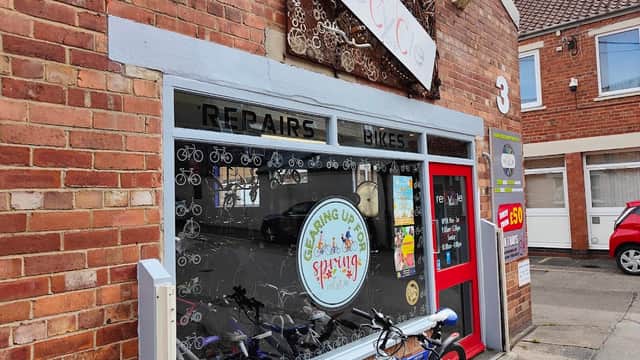 Brick storefront with "REPAIRS BIKES" signage, bicycle-themed decor, and colorful bikes outside.