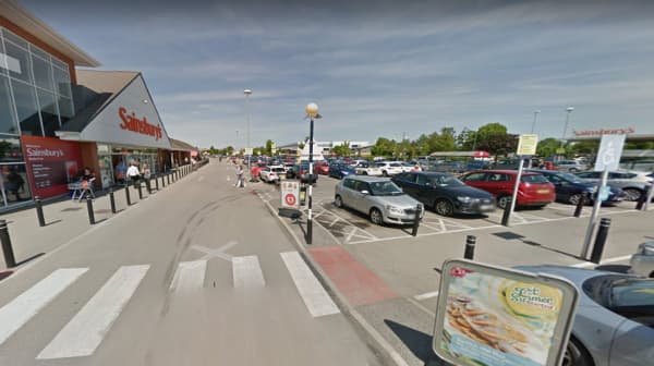 Pay & Display parking area outside Sainsbury's in Earswick, with cars parked and signage visible under clear skies.