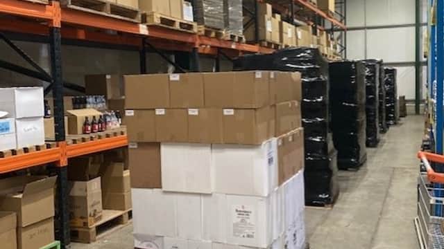 A warehouse interior with stacked pallets of boxed beer and shelves filled with various beverages in Tockwith, Yorkshire.