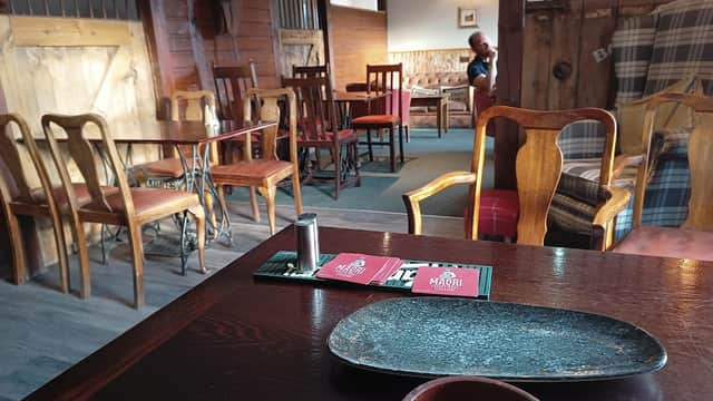Cozy interior of Comus Inn with wooden furniture, a table setting, and a glimpse of patrons in the background.