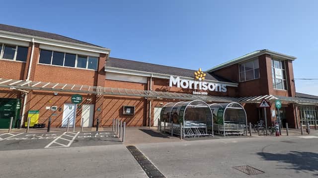Morrisons supermarket entrance at Foss Island Retail Park, with shopping carts and clear blue sky above.