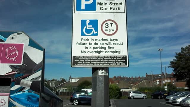 Main Street Car Park sign with parking regulations, blue sky, and cars in the background.