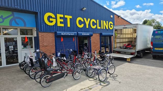 Bicycle shop exterior with various bikes displayed outside and a delivery truck parked nearby under a blue sky.