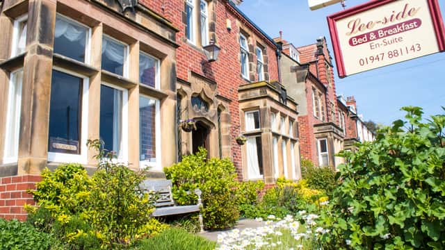 Charming brick hotel with large windows, lush garden, and a sign for "Lee-Side Bed & Breakfast" in Fylingthorpe.