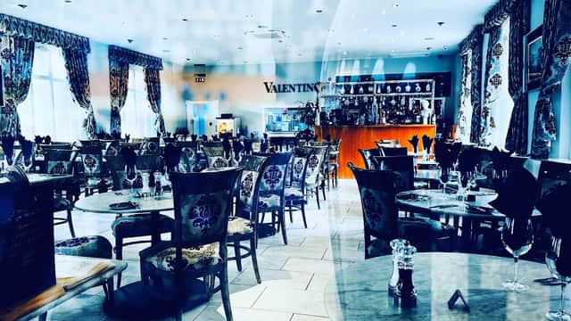 Elegant restaurant interior with ornate chairs, tables set for dining, and decorative curtains in a bright, inviting space.
