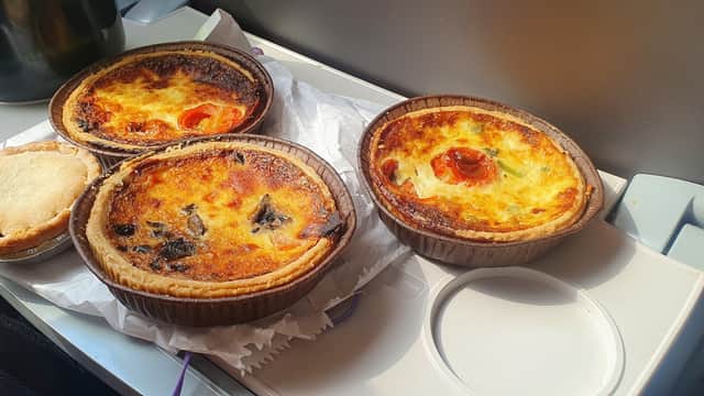 Three savory pastries on a tray, including a quiche and a pie, with golden crusts and colorful toppings.