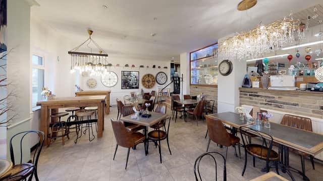Cozy cafe interior with wooden tables, vintage decor, and chandeliers, featuring a warm and inviting atmosphere.